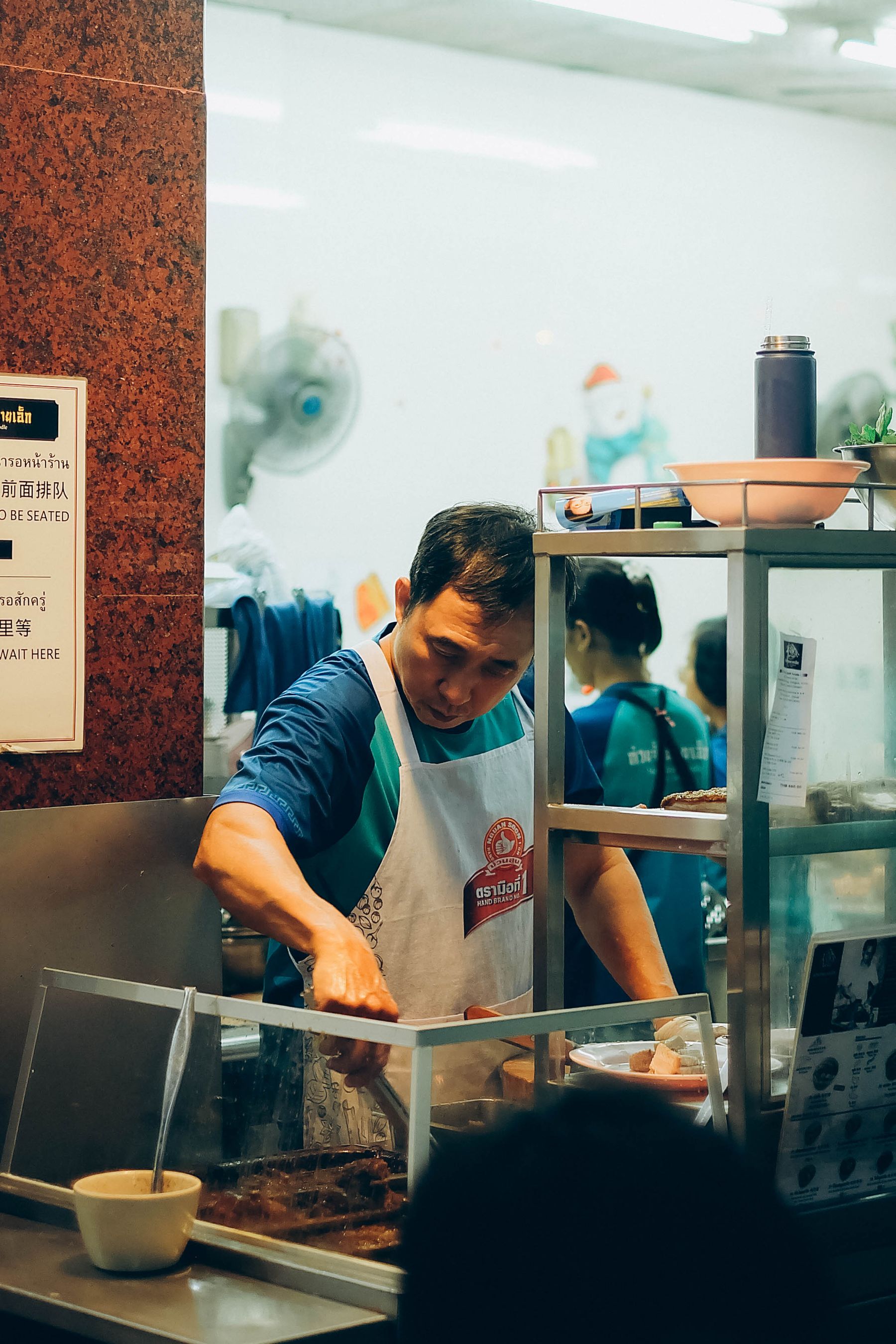 A vendor cooking over a wok at a Bangkok night market stall