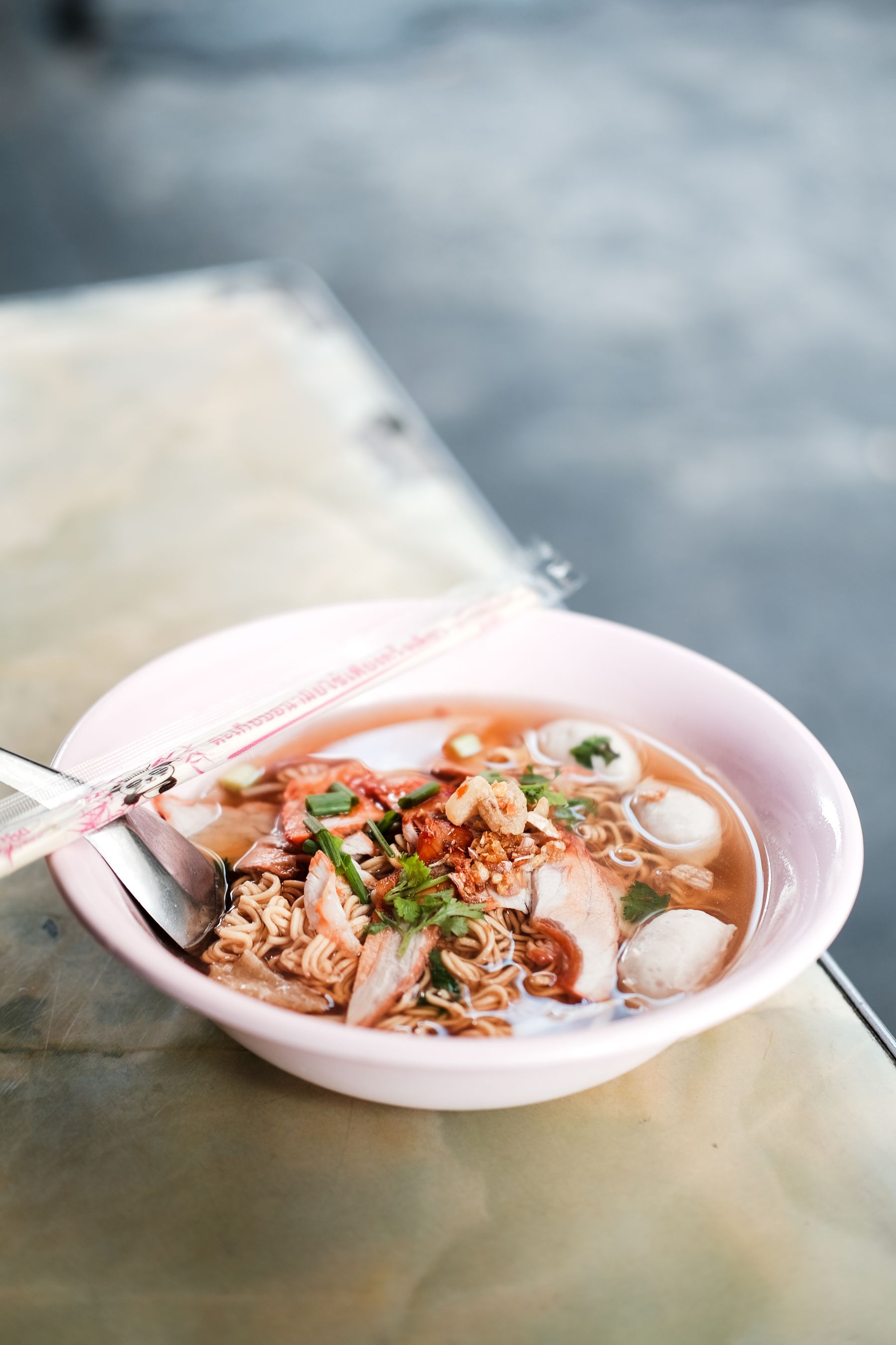 A Thai noodle soup served in a bowl with chopsticks