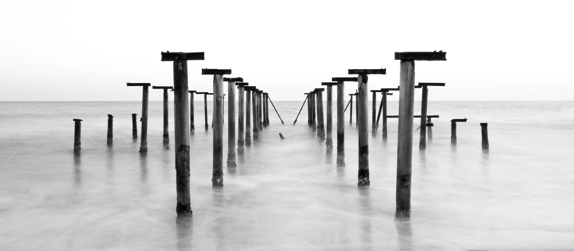 A wooden pier on stilts reaching out over clear water