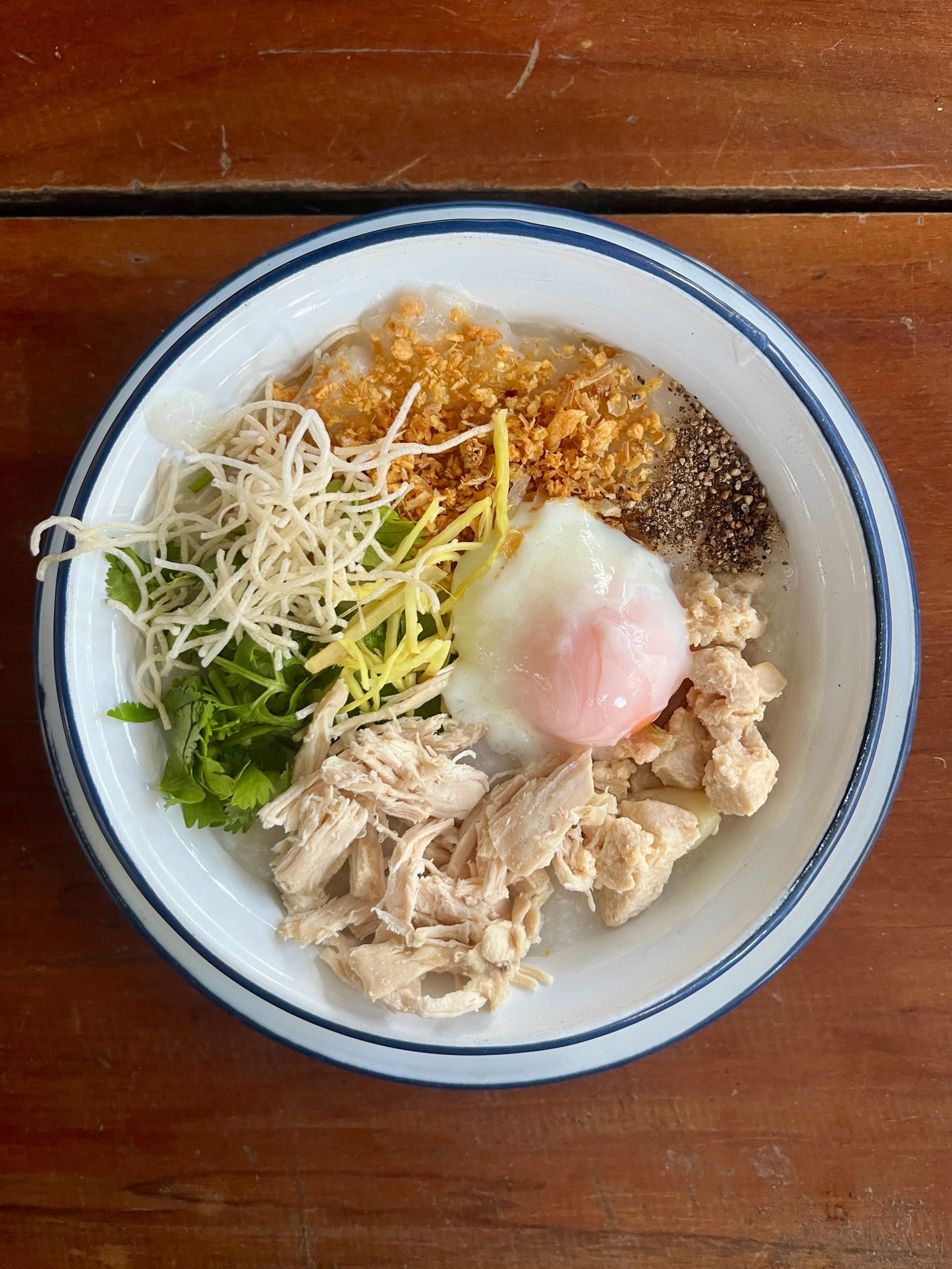 Thai jok: chicken rice porridge topped with a soft-boiled egg, ginger, coriander and crispy garlic