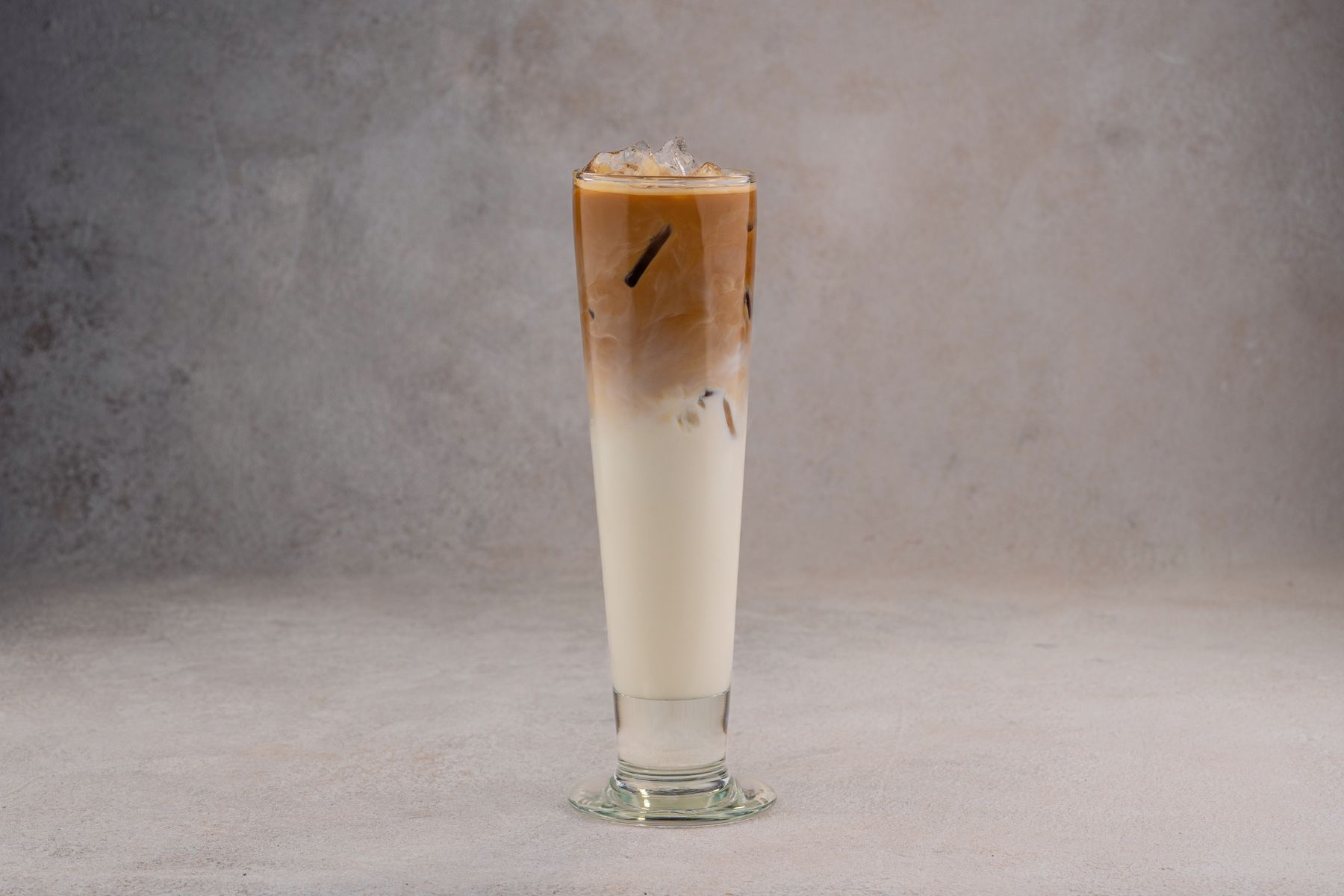 Iced coffee layered with condensed milk in a tall glass