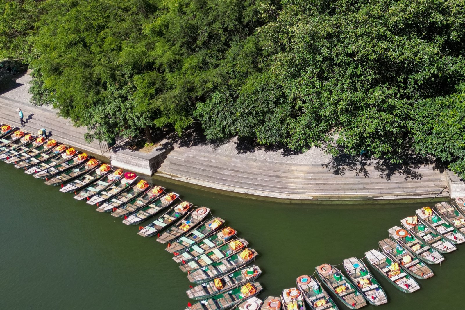 Boats moored along a green riverbank, seen from above