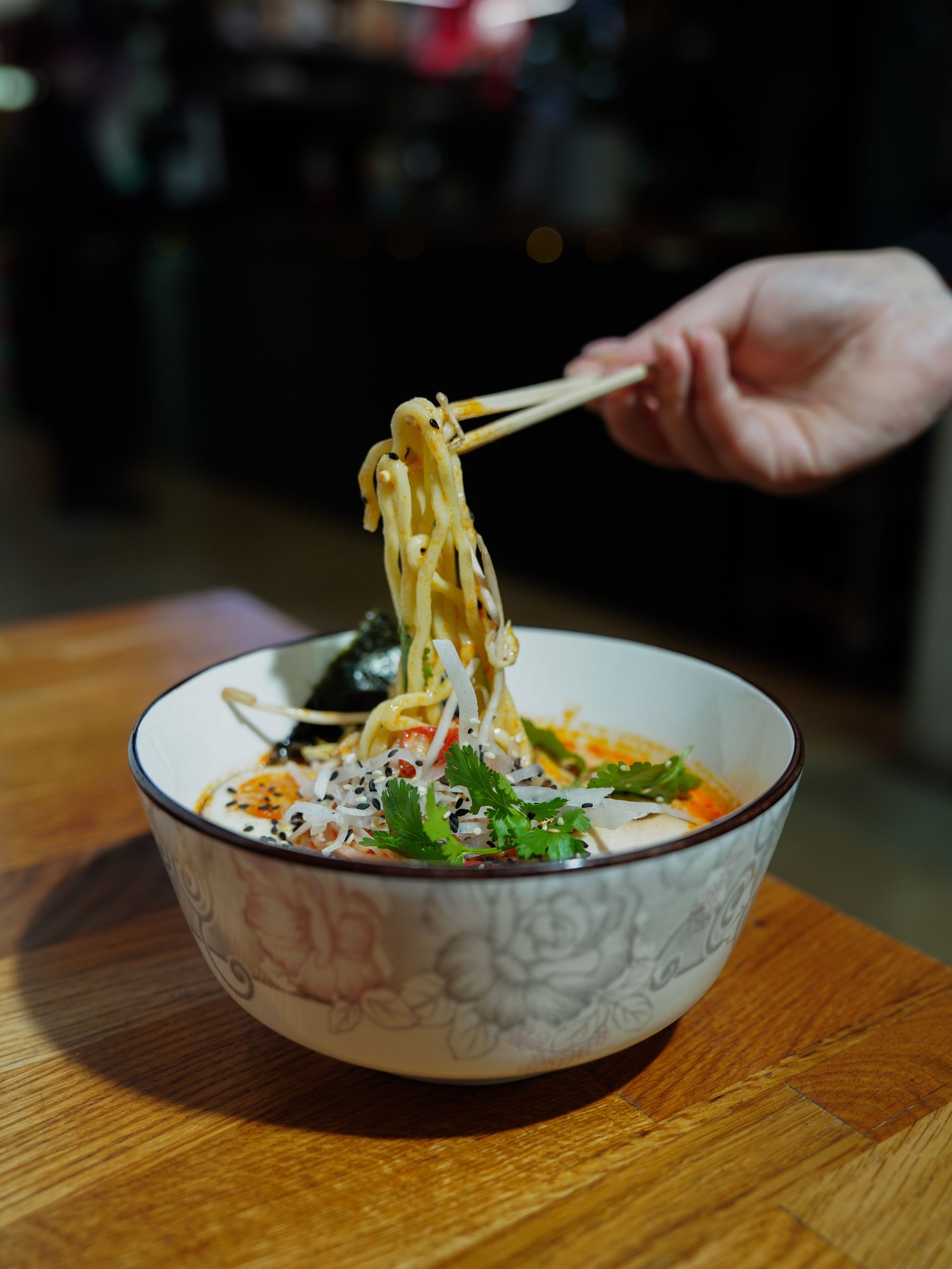 Chopsticks lifting rice noodles from a bowl of Vietnamese soup